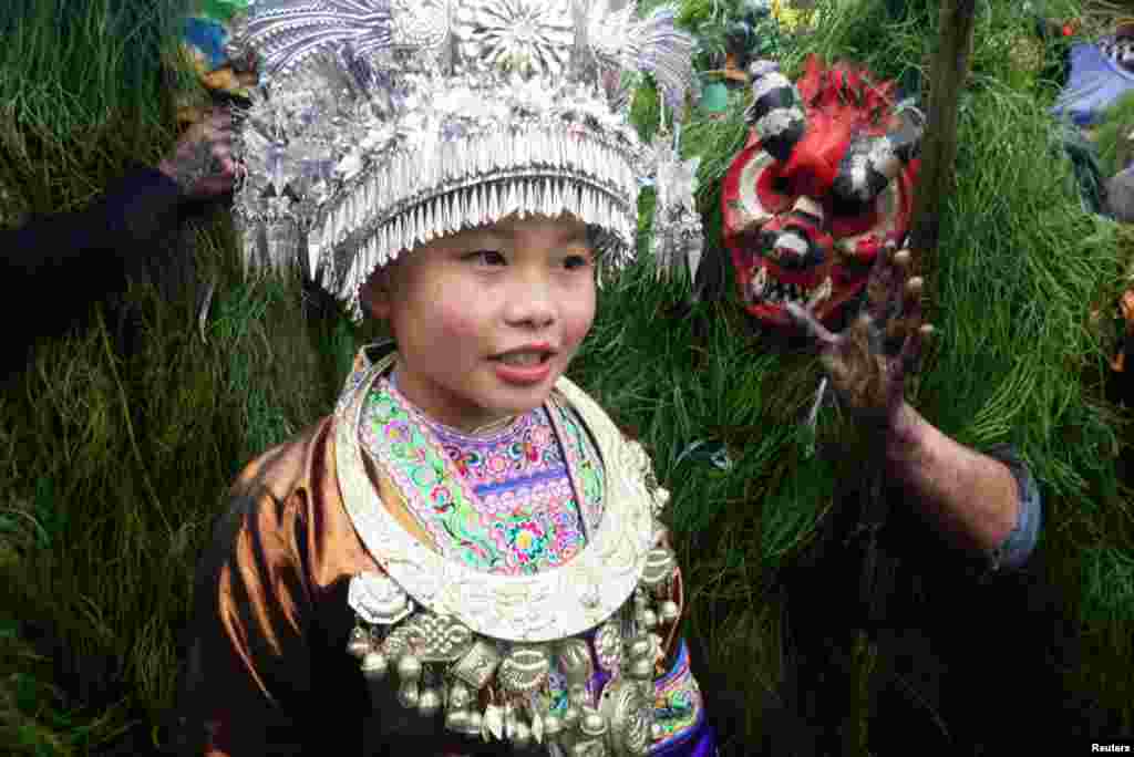 An ethnic Miao woman poses with Miao men dressed as &quot;Manghao&quot; during an event to celebrate the Manghao Festival at Rongshui Miao Autonomous County, in Liuzhou, Guangxi Zhuang Autonomous Region, China, Feb. 13, 2019.
