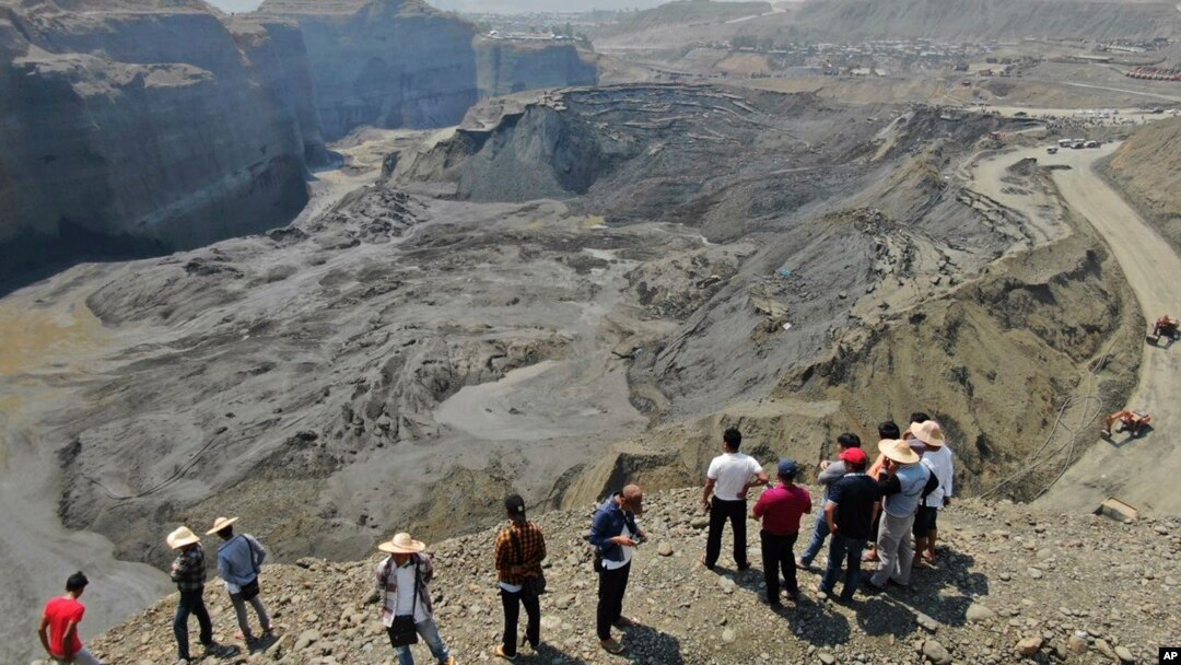 People stand atop a ridge overlooking the scene of a mudslide at a jade gemstone mining site, April 23, 2019, in Hpakant area of Kachin state, northern Myanmar. 