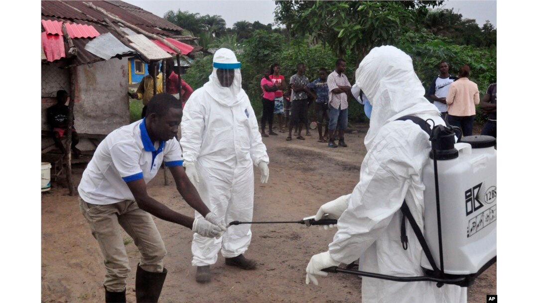 FILE - Health workers wash their hands after taking a blood specimen from a child to test for the Ebola virus in a area were a 17-year old boy died from the virus on the outskirts of Monrovia, Liberia.