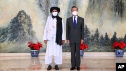 In this photo released by China's Xinhua News Agency, Taliban co-founder Mullah Abdul Ghani Baradar, left, and Chinese Foreign Minister Wang Yi pose for a photo during their meeting in Tianjin, China, Wednesday, July 28, 2021. (Li Ran/Xinhua via AP)