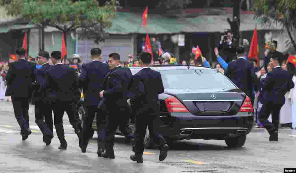 North Korean bodyguards run along a limousine transporting North Korea&#39;s leader Kim Jong Un upon his arrival at the border town with China in Dong Dang, Vietnam.