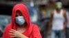 A woman wearing a protective mask walks outside a village that was placed under lockdown due to the number of COVID-19 cases among residents in Manila, Philippines, on March 11, 2021. 