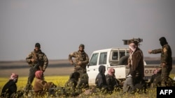 FILE - Men suspected of being Islamic State group fighters arrive at a screening point run by U.S.-backed Syrian Democratic Forces, where suspected jihadists, many of them wounded, were being interrogated outside Baghuz in northeastern Syria, March 6, 2019.
