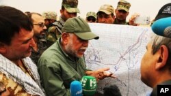 FILE - Hadi al-Amiri, leader of the Badr Brigades Shiite militia, explains a battle plan to his fighters on the outskirts of Fallujah, Iraq, June 1, 2015. A base hit by a drone attack, July 19, 2019, reportedly belonged to the Badr Brigades.