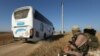 Members of Hayat Tahrir al-Sham group, led by Syria's former al-Qaida affiliate, watch as buses get ready to enter the towns of Foua and Kefraya to evacuate their residents, July 18, 2018.