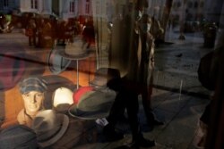 Una pareja con mascarilla se refleja en el vidrio de una vitrina de una tienda de sombreros en el centro de Lisboa, Portugal, el miércoles 2 de diciembre de 2020.