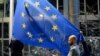 Workers replace the British flag outside the European Parliament building with the European Union flag, in Brussels, Belgium, Jan. 31, 2020