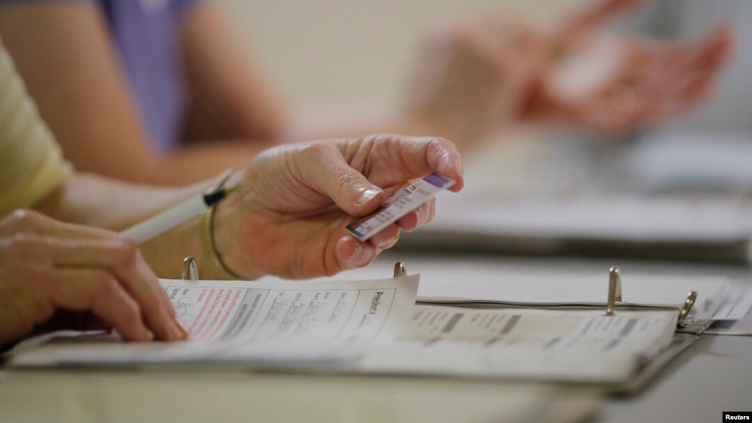 FILE - An election worker checks a voter's drivers license as North Carolina's controversial "Voter ID" law goes into effect for the state's presidential primary election at a polling place in Charlotte, North Carolina, March 15, 2016. 