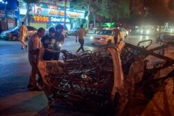 Passersby look at all that is left of a minibus that was destroyed in afiery explosion in Cairo, Egypt. (H. Elrasam for VOA)