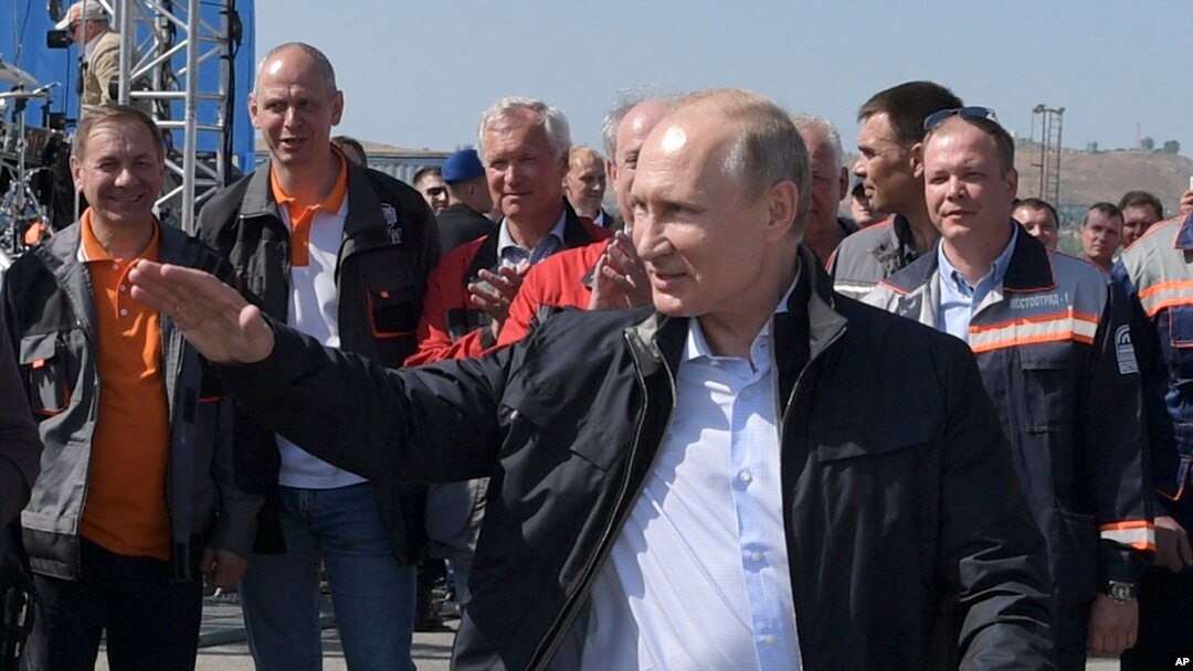 Russian President Vladimir Putin gestures while speaking to a group of workers after driving a truck to officially open the much-anticipated bridge linking Russia and the Crimean peninsula the opening ceremony near in Kerch, Crimea, Tuesday, May 15, 2018.