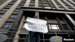 FILE - A lone activist protests restrictive law targeting foreign-funded NGOs working in Russia, outside the Duma, Russia's lower house of parliament, in Moscow.