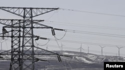 FILE - Power lines and wind turbines are seen at a wind and solar energy storage and transmission power station of State Grid Corporation of China, in Zhangjiakou of Hebei province, China, March 18, 2016. 