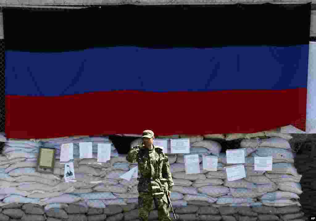 A pro-Russian gunman speaks by phone in front of the city hall decorated with the flag of self-proclaimed Donetsk People's Republic, in the center of Slovyansk, eastern Ukraine, May 8, 2014.
