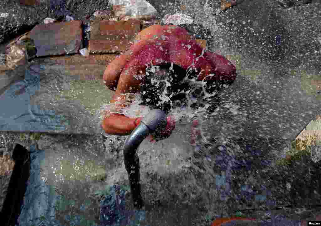 A man bathes at a roadside municipal tap in a market area of Kolkata, India.