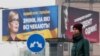 FILE - A woman stands in front of pre-election posters of opposition politician Yulia Tymoshenko and Ukrainian President Petro Poroshenko in Kyiv, Ukraine, Feb. 20, 2019. 