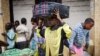 Kadogo Ombeni, 27, stands near the Rwandan border with Congo with a suitcase on his head after fleeing his home in the Bujovu Kabutembo district of Goma, in the east of the Democratic Republic of the Congo, November 20, 2012.