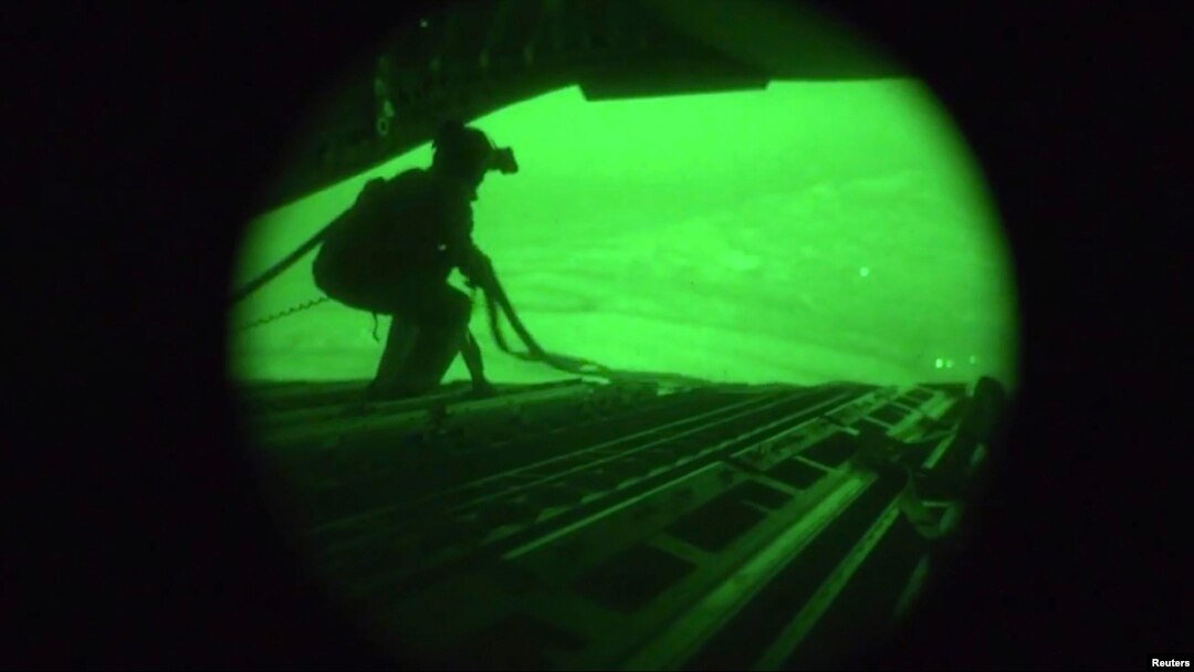 FILE - Still from night-vision footage shows Air Force personnel retrieving straps after U.S. military airdrop of food and water for thousands of Iraqi citizens threatened by Islamic State militants in 2014.