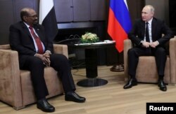 FILE - Russian President Vladimir Putin talks with Sudanese President Omar al-Bashir during their meeting in the Black Sea resort of Sochi, Russia, Nov. 23, 2017.