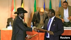 FILE - South Sudan's President Salva Kiir, left, and South Sudan's rebel commander Riek Machar exchange documents after signing a cease-fire agreement in Ethiopia's capital, Addis Ababa, Feb. 1, 2015.