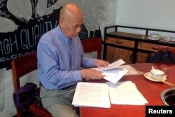 FILE - Xu Xiaoshun, the father of activism blogger Wu Gan, who was detained in what is known as the "709" crackdown, looks through documents about his son's case in a restaurant in Jiangsu Province, China, June 12, 2017.