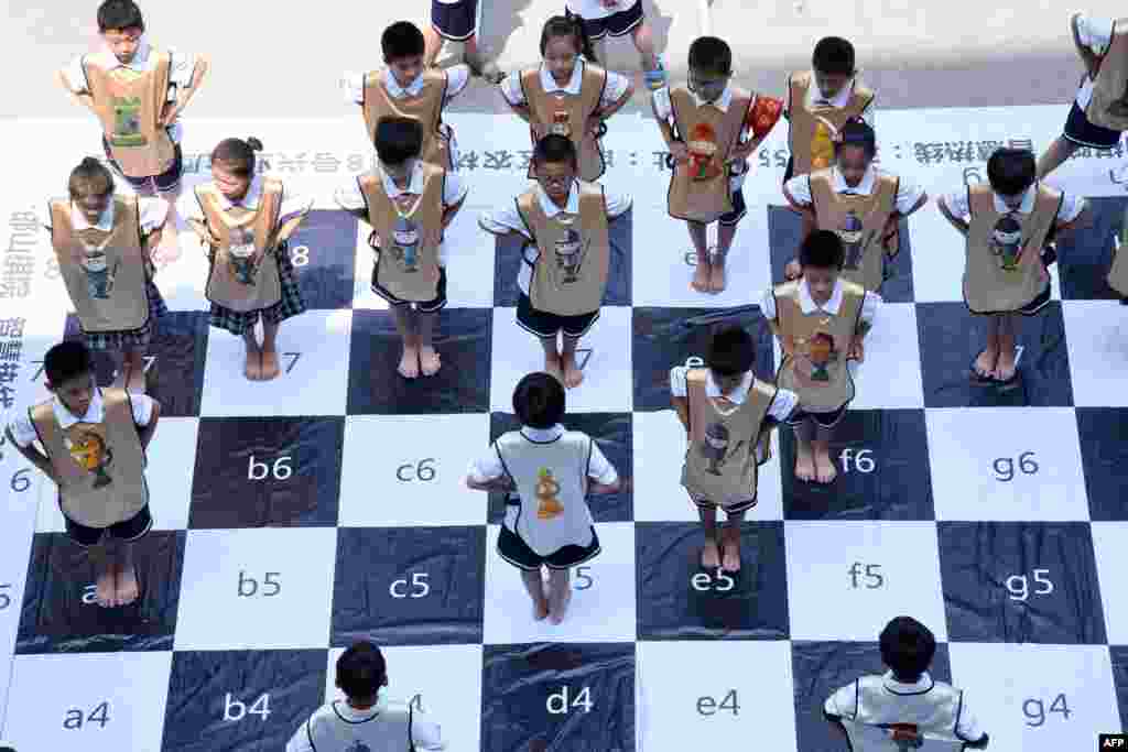 河北省邯郸市农林路小学的学生比赛"真人国际象棋"(2017年6月19日),装扮成"王、后、车、象、马、兵"的"棋子",在大型棋盘上变换位置。