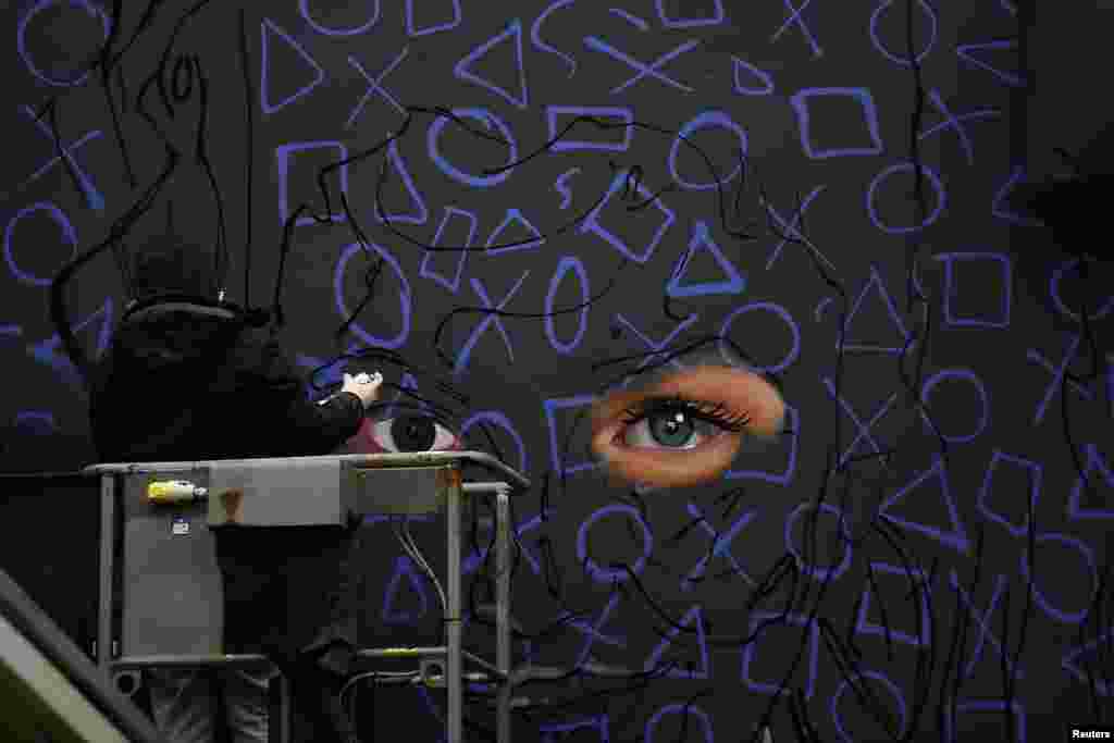 A graffiti artist spray-paints a new mural of 'Derry Girls' television show in Londonderry, Northern Ireland.