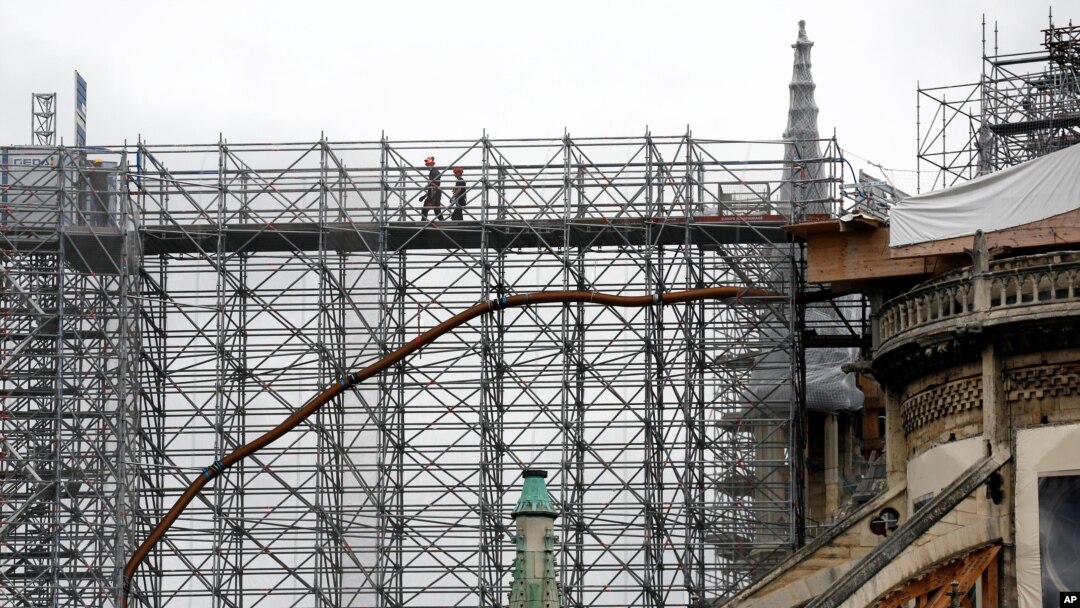 Workers walk through a scaffolding at Notre Dame cathedral, July 10, 2020 in Paris. Notre Dame Cathedral will be rebuilt just the way it stood before last year's devastating fire.