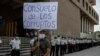 Un hombre sostiene un cartel con un mensaje que reza "consuelo de los corruptos", durante una protesta exigiendo la renuncia de la fiscal general María Consuelo Porras y el ministro del Interior Gendri Reyes, el 21 de mayo 2021.