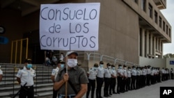 Un hombre sostiene un cartel con un mensaje que reza "consuelo de los corruptos", durante una protesta exigiendo la renuncia de la fiscal general María Consuelo Porras y el ministro del Interior Gendri Reyes, el 21 de mayo 2021.