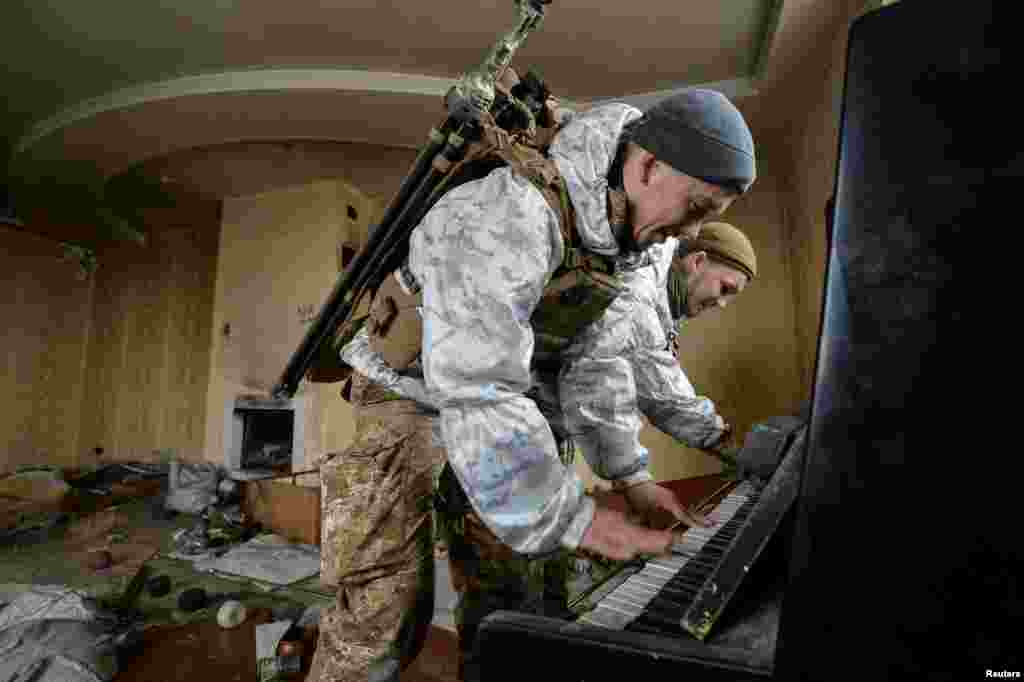 Members of the Ukrainian Armed Forces play the piano in a house that was destroyed by fighting, near their position on the front line in the Donetsk region, Feb. 4, 2019.