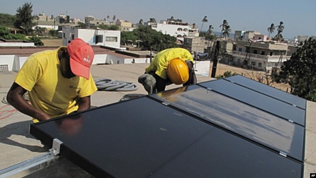 Prosolia technicians Mamadou Ba, left, and Mouhamed Diedhiou install solar panels on a vocational school in Dakar, Senegal, Dec. 1, 2011.
