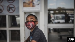 TOPSHOT - A boy wears a face mask as a preventive measure against the spred of the COVID-19 coronavirus as he queues outside Makro in Soweto, Johannesburg, on March 24, 2020. - South African President Cyril Ramaphosa on March 23, 2020 announced a 21…