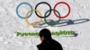 FILE - A man walks by the Olympic rings with a sign of 2018 Pyeongchang Olympic Winter Games, in Pyeongchang, South Korea, Feb. 3, 2017. 