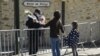 A woman hands flowers to an officer to be taken to the police station where a female police worker was stabbed to death two days earlier, in Rambouillet, southwest of Paris, France, April 25, 2021. 