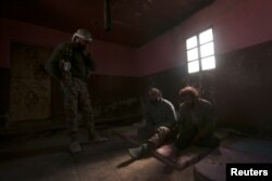 FILE - A Syrian Democratic Forces fighter stands near who he said were Islamic State fighters held prisoners, north of Raqqa, Syria, March 8, 2017.