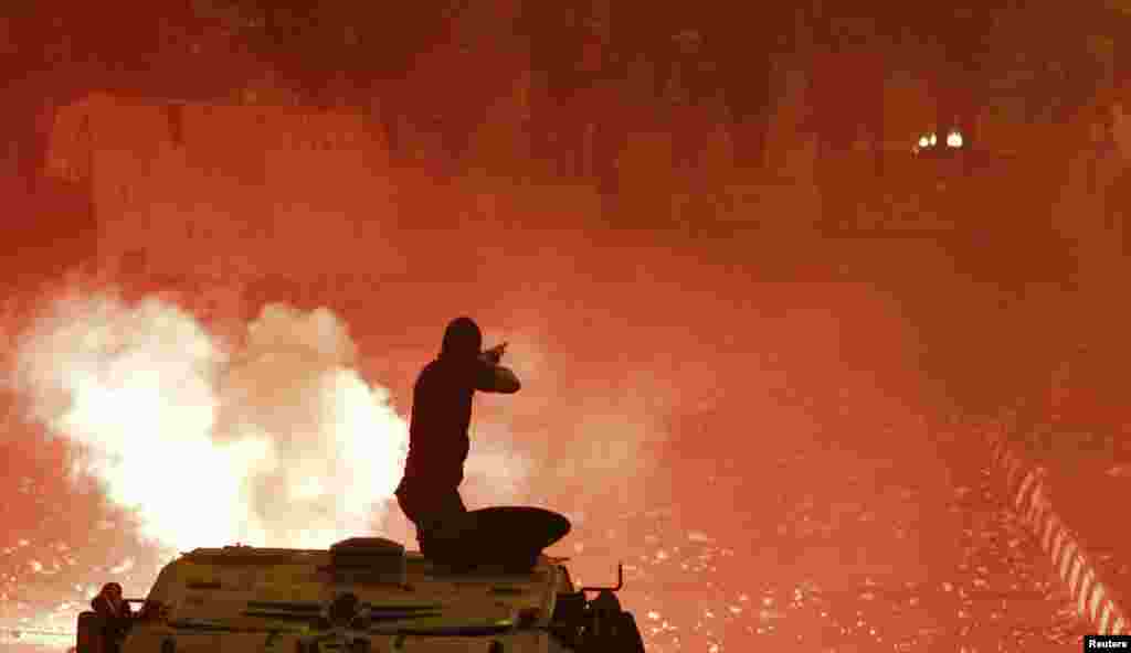 A riot police officer, on a armored personnel carrier, fires rubber bullets at members of the Muslim Brotherhood and supporters of ousted Egyptian President Mohamed Morsi along a road at Ramsis square, Cairo, Oct. 6, 2013.