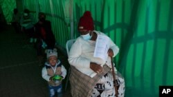 An elderly woman with a young child queues to receive her Pfizer COVID-19 vaccine, at a clinic at Orange Farm, near Johannesburg, Thursday, June 3, 2021. South Africa began vaccinating its elderly citizens nearly three weeks ago. (AP Photo/Denis…