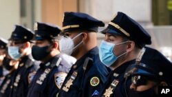 FILE - New York Police Department officers in masks stand during a service at St. Patrick's Cathedral in New York to honor 46 colleagues who have died of COVID-19-related illnesses, Oct. 5, 2020.
