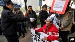 A policeman points to a supporter of Southern Weekly newspaper in a wheelchair before taking him away during a protest in Guangzhou, Guangdong province, China, Jan. 10, 2013. 