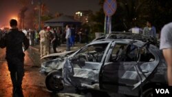 People survey the aftermath of a fiery car crash outside the National Cancer Institute in Cairo, Egypt, Monday, Aug. 5, 2019. 