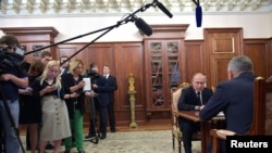 Journalists stand near Russia's President Vladimir Putin as he meets with Defense Minister Sergei Shoigu to discuss a recent incident with a Russian deep-sea submersible, which caught fire in the area of the Barents Sea, in Moscow, Russia, July 2, 2019. 