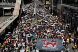 FILE - Anti-extradition bill protesters march during the anniversary of Hong Kong's handover to China, in Hong Kong, July 1, 2019.