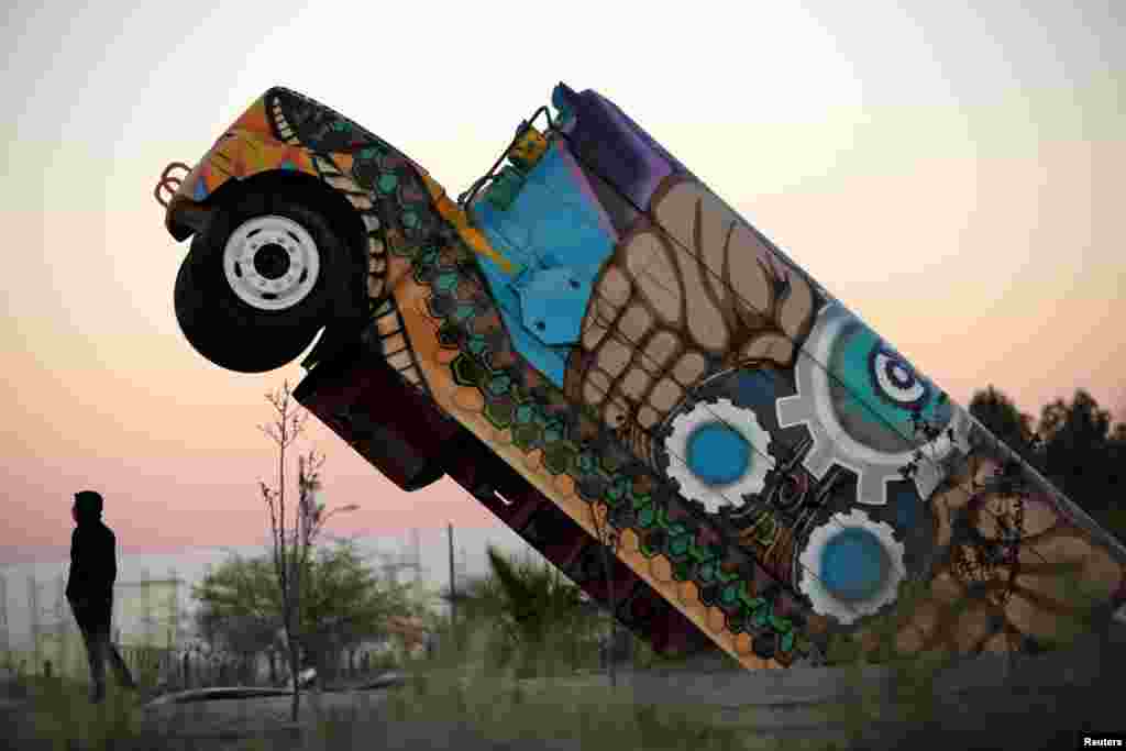 A man stands next to the &#39;Ser Fronterizo&#39; monument, a retired U.S. school bus cut in half and erected to recognize the employees of assembly factories who use public transportation daily to get to work, in Ciudad Juarez, Mexico, March 14, 2019.