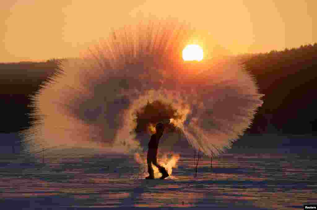 Winter outdoor sports enthusiast Olesya Ushakova poses for an acquaintance (not pictured) while throwing hot water into subzero air as part of the 'Dubak Challenge,' a social media trend popular in Russia, during sunset outside the Siberian city of Krasnoyarsk.