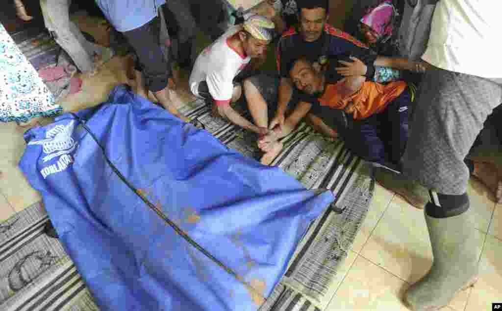 A man reacts near a body bag containing the body of his relative who was killed by a landslide in Sirnaresmi, West Java, Indonesia. The landslide triggered by torrential rain has killed a number of people and left dozens others missing on the main island of Java.