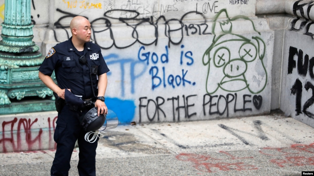Un agente de la policía de Nueva York protege una de las zonas vandalizadas por los manifestantes que solicitan un recorte al presupuesto de la policía de la ciudad.