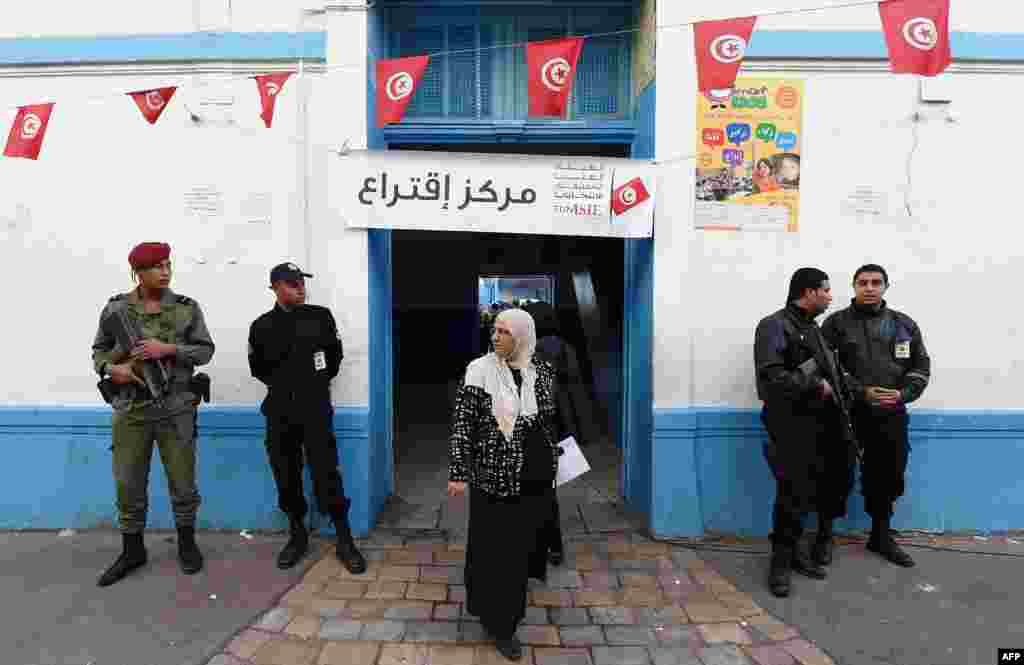 Tunisian security officers stand guard outside a polling station during Tunisia's first presidential election since the 2011 revolution, in the center of Tunis, Nov. 23, 2014.