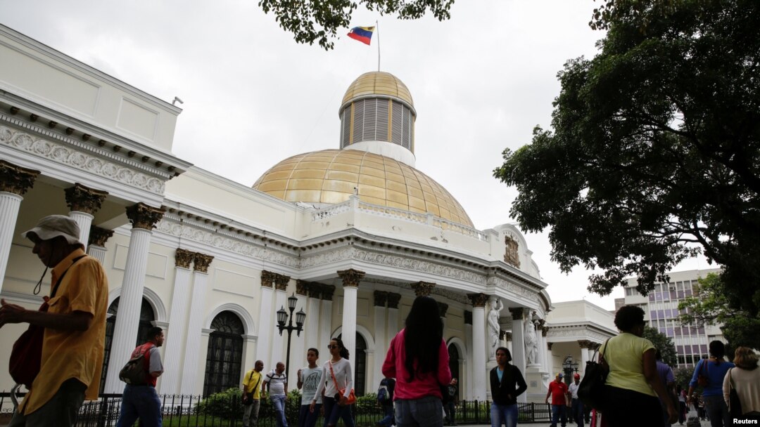 Personas pasan frente al edificio de la Asamblea Nacional durante una sesión parlamentaria en Caracas, el 14 de diciembre de 2016. 