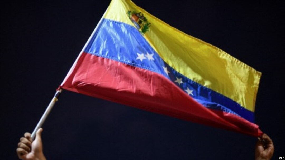 Un hombre muestra una bandera venezolana en protesta junto a familiares y amigos de migrantes venezolanos que murieron cuando se hundió un barco que los transportaba a Trinidad y Tobago, en Güiria, Venezuela, el 18 de diciembre de 2020.