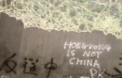 FILE - Damage to the Legislative Council complex following a break-in by protesters is seen during a media tour, July 3, 2019, in Hong Kong. The Chinese characters read "No Extradition to China."